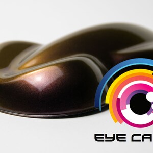 May include: A metallic brown car paint sample with a deep, rich color and a subtle shimmer. The sample is shaped like a teardrop and is sitting on a white surface. The Eye Candy logo is visible in the lower right corner of the image.
