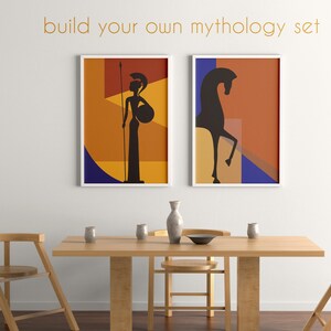 May include: Two framed art prints with abstract designs of mythological figures. One features a warrior with a spear and shield, the other a rearing horse. The text "build your own mythology set" is above the prints. A wooden table and chairs are in the foreground.