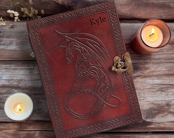 May include: A brown leather journal with a dragon design embossed on the cover. The journal has a brass clasp and is personalized with the name "Kyle".