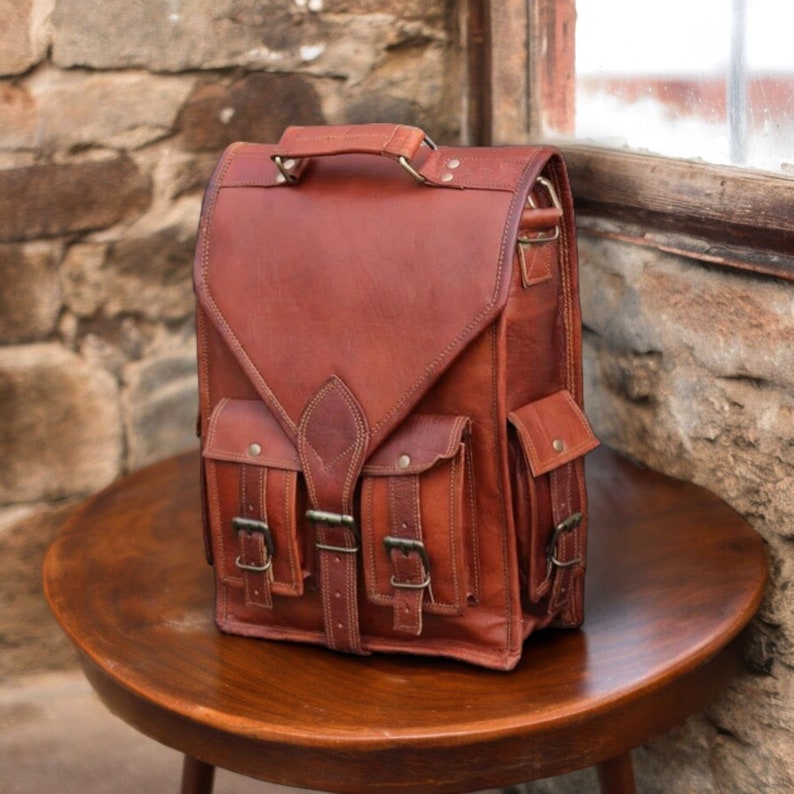A vintage convertible leather backpack Messenger bag placed on  table against a stone wall. It has a practical compact design. Concealed push locks are there for closure. Ideal for birthday gifts, personalized gifts, gifts for him/her.