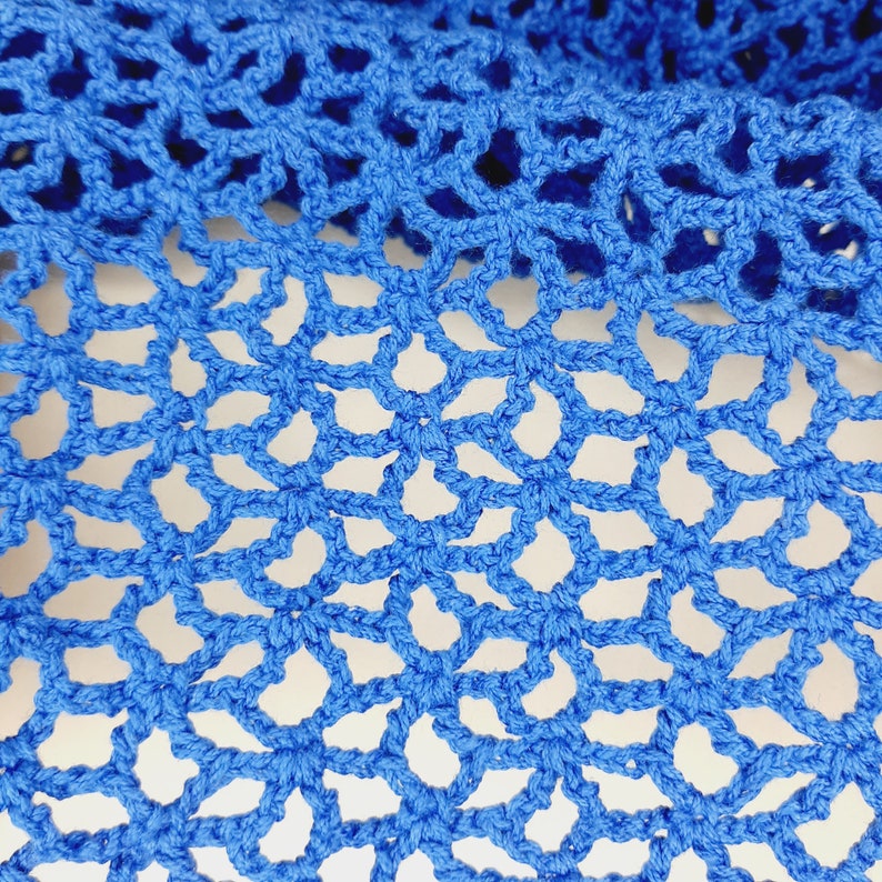 May include: Close-up of a blue crocheted fabric with a delicate, intricate pattern. The fabric is made of yarn and has a soft, textured surface.