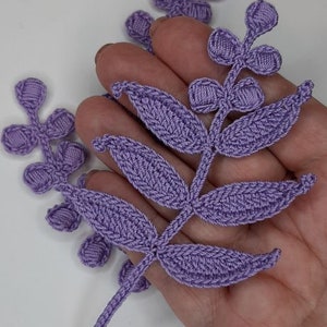 May include: A set of three purple crocheted flower embellishments. The embellishments are in the shape of leaves and flowers. The embellishments are perfect for adding a touch of handmade charm to any project.