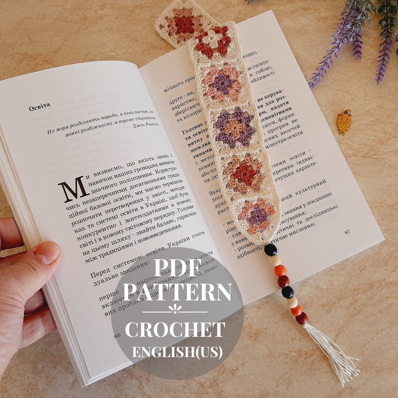 May include: A crocheted bookmark with a granny square pattern in shades of pink, beige, and brown. The bookmark has a tassel and wooden beads in shades of brown, orange, red, and blue.