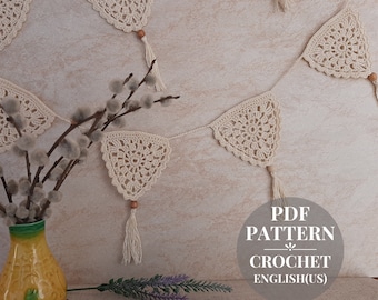 May include: A crochet garland with white triangle flags and tassels. The garland is hanging on a wall with a vase of pussy willow branches in the foreground. The text "PDF PATTERN CROCHET ENGLISH(US)" is visible in the lower right corner of the image.