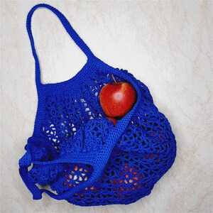 May include: A blue crocheted mesh bag with red apples inside. The bag is made of a soft, lightweight material and has a drawstring closure.