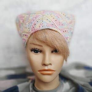 May include: A crocheted hat in pastel pink, blue, and yellow colors. The hat has a geometric pattern and is made with a soft yarn.