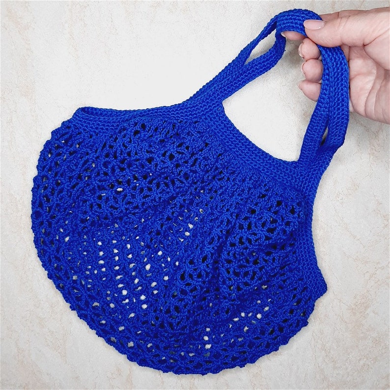 May include: A blue crocheted tote bag with a wide, open top and two handles. The bag is made of a fine, delicate yarn and has a lacy, openwork design.