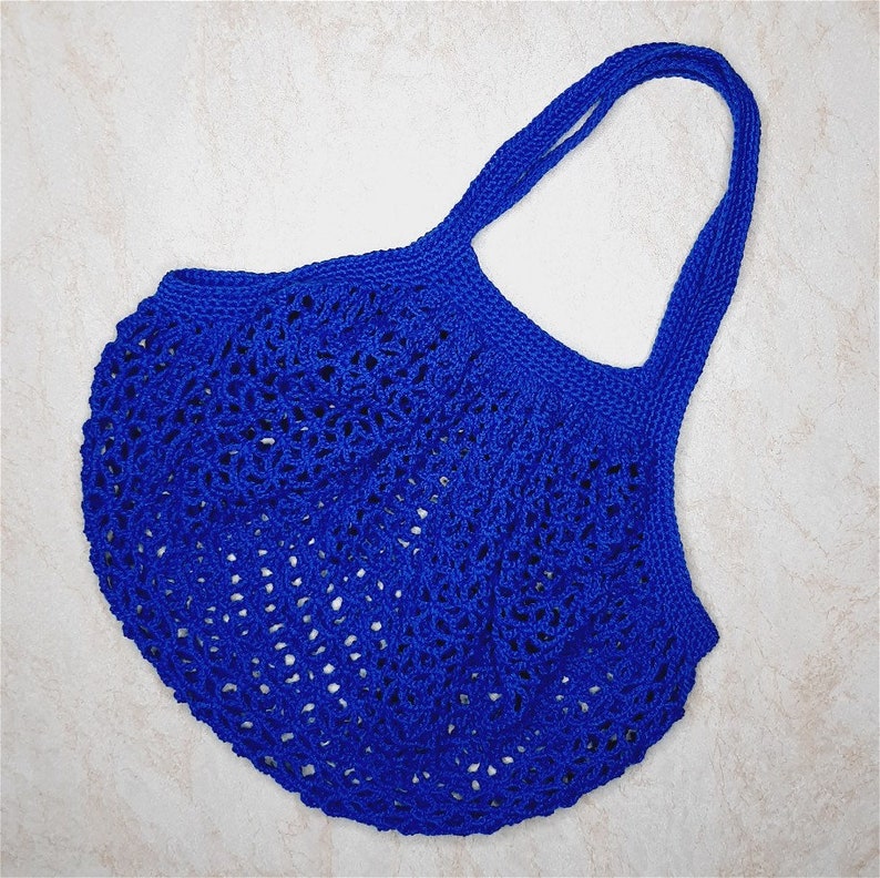 May include: A blue crocheted tote bag with a wide, open top and a single handle. The bag is made of a delicate, open-weave material.