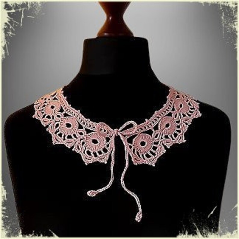 May include: A delicate pink crocheted collar with a tie closure. The collar is made of fine yarn and features a delicate floral pattern.