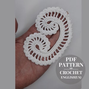 Op de afbeelding: Wit crochet-patroon in de vorm van een dubbele spiraal. Het patroon wordt in een hand gehouden. De tekst "PDF PATTERN CROCHET ENGLISH(US)" staat in de rechterbenedenhoek van de afbeelding.