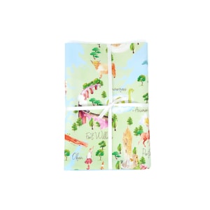 May include: A green and blue fabric with a map of Scotland featuring various landmarks and animals. The fabric is wrapped in a white ribbon and tied in a bow. The text "Fort William", "Oban", "Inverness", "Aviemore", and "Perth" are visible on the fabric.
