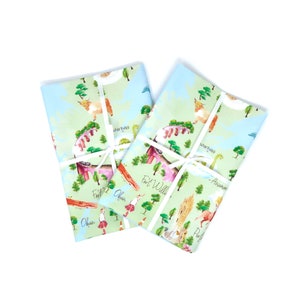 May include: Two blue and green fabric tea towels with a map of Scotland design. The map features various cities and towns, including Oban, Fort William, Inverness, and Aberdeen. The design also includes illustrations of Highland cows, Nessie the Loch Ness Monster, and other Scottish icons.