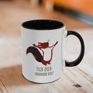 Könnte beinhalten: Weiße Keramiktasse mit schwarzem Rand und Henkel. Die Tasse zeigt ein Cartoon-Eichhörnchen mit ausgestreckten Armen und dem Text "FICK DICH SOOOOOO VIEL!"