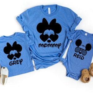 May include: Three blue t-shirts with black Mickey Mouse and Minnie Mouse character designs. The shirts say "mommy", "Grey", and "Reid".