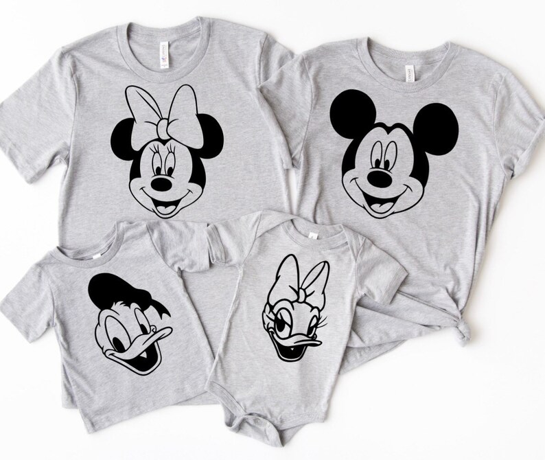 May include: A set of four gray t-shirts featuring black and white cartoon character faces. The shirts feature Mickey Mouse, Minnie Mouse, Donald Duck, and Daisy Duck.