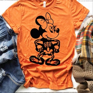 May include: Orange t-shirt with a black skeleton Minnie Mouse graphic. The shirt is made of a soft, comfortable material.