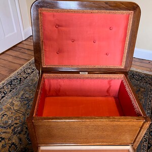 May include: An antique wooden storage box with a red fabric lining and a pull-out drawer. The box has a hinged lid and is decorated with a gold trim.