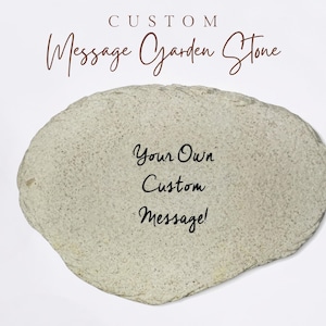 May include: An oval-shaped, light beige garden stone with a speckled texture. The text 'CUSTOM Message Garden Stone' appears at the top, and the center features the black printed text 'Your Own Custom Message!' in a cursive, handwritten-style font.