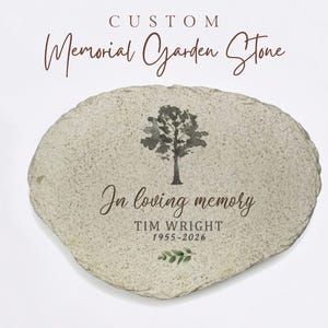 May include: A custom memorial garden stone with a textured, light-colored surface. The stone features a dark gray tree illustration, the text "In loving memory", the name "TIM WRIGHT", the dates "1955-2026", and a small green leaf graphic.