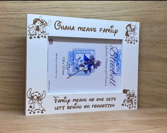 May include: A white rectangular photo frame featuring brown engraved illustrations of the character Stitch from Lilo and Stitch. The text reads Ohana means family and Family means no one gets left behind or forgotten. It holds a 7 by 5 inch photo.