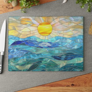 A stained glass style cutting board with a blue and green ocean scene and a yellow sun in the sky.