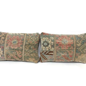 Könnte beinhalten: Zwei rechteckige Kissen mit Patchwork-Design. Die Kissen weisen eine Mischung aus gedämpften Farben auf, darunter Grün, Rot und Beige, mit komplizierten Mustern. Die Kissen sind nebeneinander vor einem weißen Hintergrund platziert.