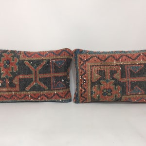 May include: Two rectangular throw pillows with a traditional Turkish kilim pattern in shades of red, blue, and green. The pillows have a woven texture and a fringed edge.