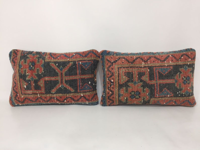 May include: Two rectangular throw pillows with a traditional Turkish kilim pattern in shades of red, blue, and green. The pillows have a woven texture and a fringed edge.
