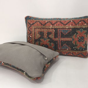 May include: Two decorative throw pillows, one with a gray fabric cover and the other with a colorful patterned fabric cover. The patterned pillow has a red, blue, and green geometric design.