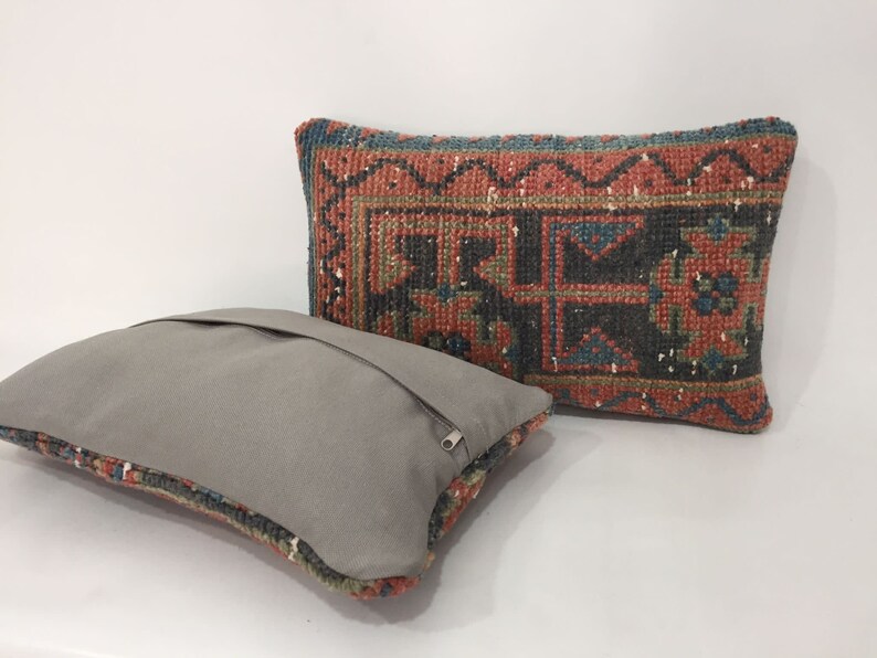 May include: Two decorative throw pillows, one with a gray fabric cover and the other with a colorful patterned fabric cover. The patterned pillow has a red, blue, and green geometric design.