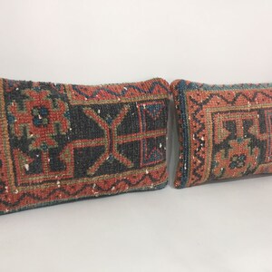 May include: Two rectangular throw pillows with a traditional Turkish kilim pattern in shades of red, blue, and green. The pillows are made of woven fabric and have a fringed edge.