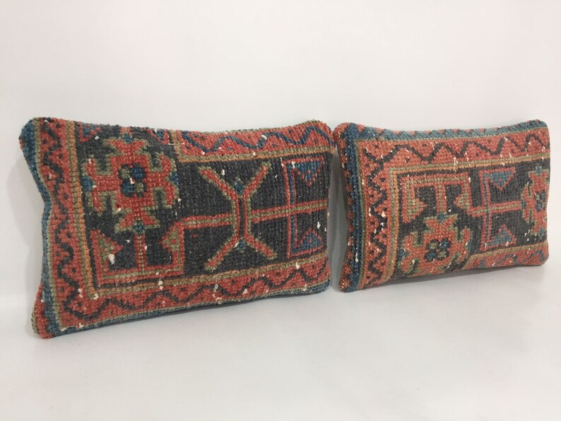 May include: Two rectangular throw pillows with a traditional Turkish kilim pattern in shades of red, blue, and green. The pillows are made of woven fabric and have a fringed edge.