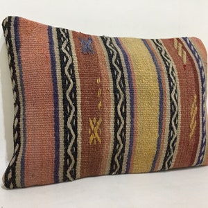May include: Rectangular pillow with a woven design. The pillow features vertical stripes in shades of pink, yellow, and brown, accented with blue and black details. The pillow is a decorative home accent.