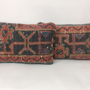 May include: Two decorative throw pillows with a traditional rug pattern in shades of red, blue, green, and black.