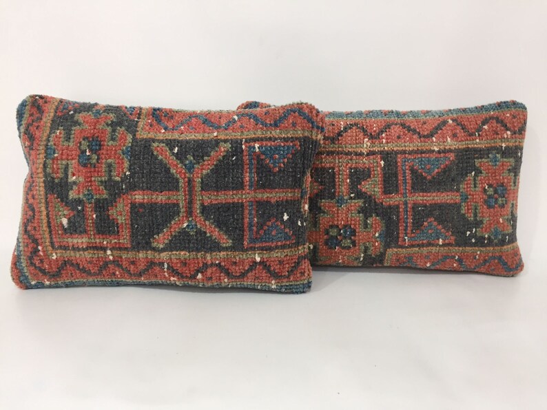 May include: Two decorative throw pillows with a traditional rug pattern in shades of red, blue, green, and black.