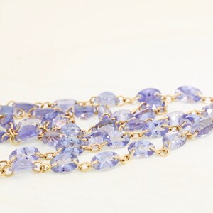 May include: A gold chain necklace with oval-shaped purple gemstones.