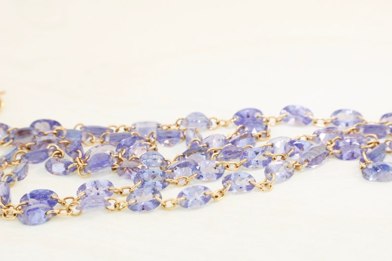 May include: A gold chain necklace with oval-shaped purple gemstones.