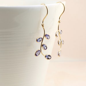 May include: A pair of gold dangle earrings with purple gemstones shaped like leaves.