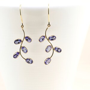 May include: A pair of gold earrings with a delicate branch design and purple gemstones.