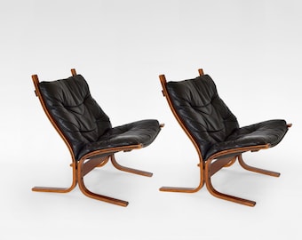 May include: A pair of lounge chairs featuring black leather upholstery with tufted detailing and curved wooden frames. The chairs have a low-profile design with a reclined backrest and a base constructed from bent wood supports.
