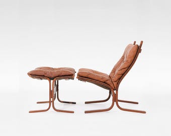 May include: A brown leather armchair and matching ottoman with a wood frame. The chair and ottoman have a tufted design.