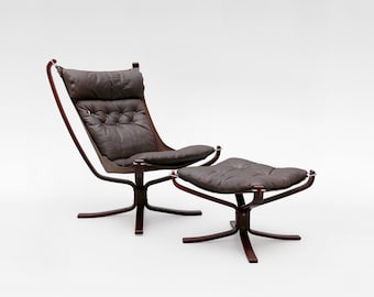 May include: A mid-century modern lounge chair and ottoman set. The chair has a dark brown leather seat and backrest with button tufting, supported by a dark wood frame. The matching ottoman has a similar design. The set is on a white background.