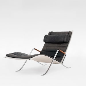 May include: A black leather lounge chair with a chrome frame and wooden armrests. The chair has a padded headrest and a footrest.