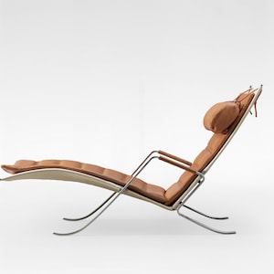 May include: A brown leather chaise lounge with a chrome frame. The chaise lounge has a curved back and a headrest.