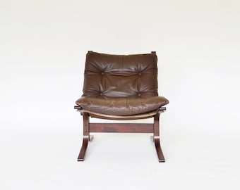 May include: A brown leather armchair with a wooden frame and a curved back. The chair has a tufted seat and a simple design.