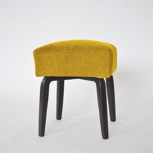 May include: A yellow upholstered stool with four black wooden legs.