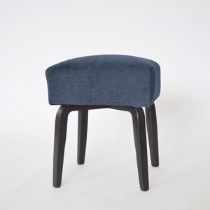May include: A blue upholstered stool with four black wooden legs.