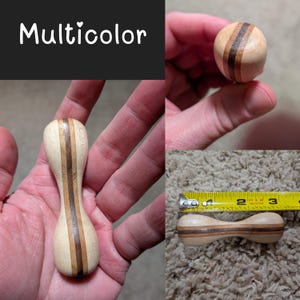 May include: A wooden dumbbell-shaped object with light and dark brown stripes. The word "Multicolor" is written in white script on a black background. The object is approximately 2.75 inches long.