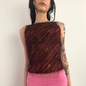 May include: A sleeveless, textured top in shades of brown and red with a diagonal stripe pattern. The top is paired with bright pink corduroy pants. The pants have silver button details and the text "roberto cavalli" on the waistband.