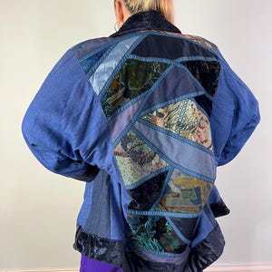 Jaren 80 blauwe patchworkjas met oversized vleermuismouwen, velours en tapijtdetails.